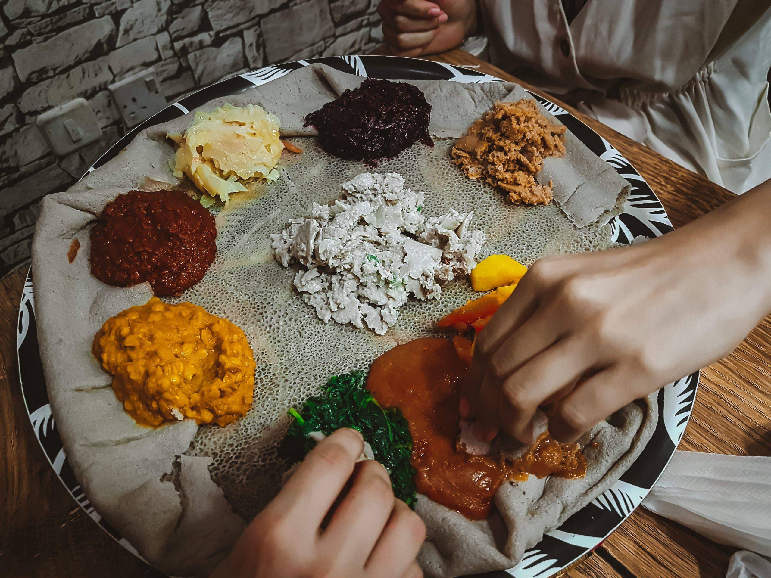 Two,Hands,Take,Food,From,Ethiopian,Food,Plate,With,Colorful